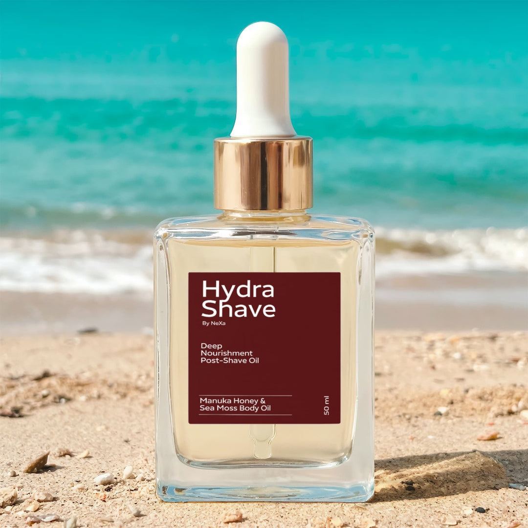 Hydra Shave bottle on a sandy beach with ocean in the background